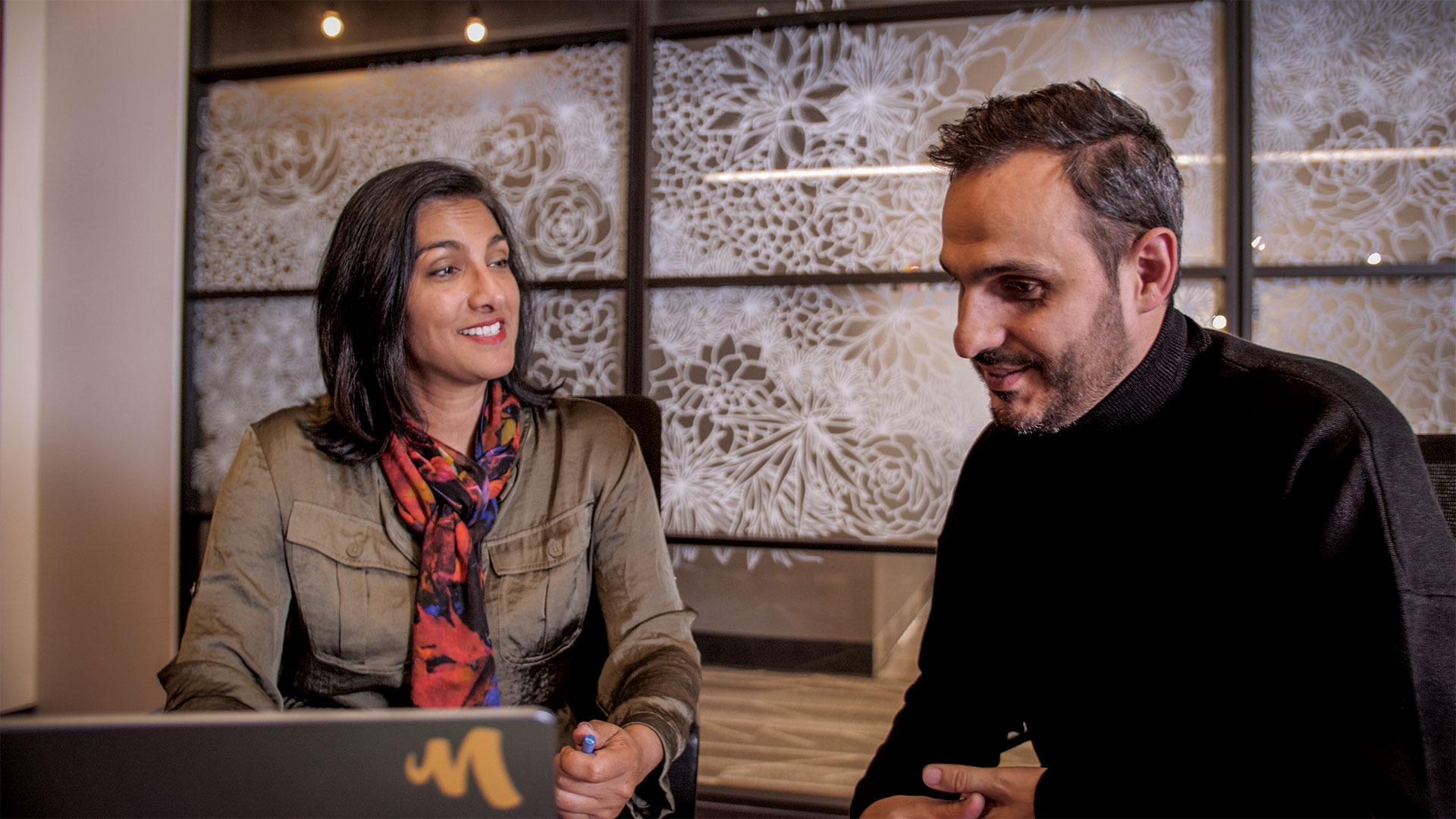 Executives from Mercury Filmworks talk to each other as they look over a laptop.